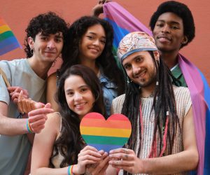 Young activists holding rainbow heart and LGBT flags promoting diversity and equality
